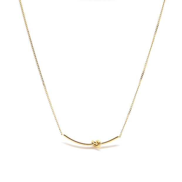 Gold love knot necklace on dainty gold chain.