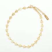Flat lay of a gold plated chain made of small dainty gold flowers connected to make one anklet, it is waterproof and tarnish proof