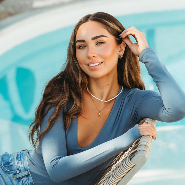 girl wearing gold necklace with pearls by the pool