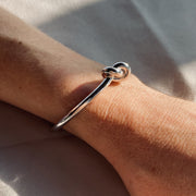 Silver adjustable love knot bracelet on arm.